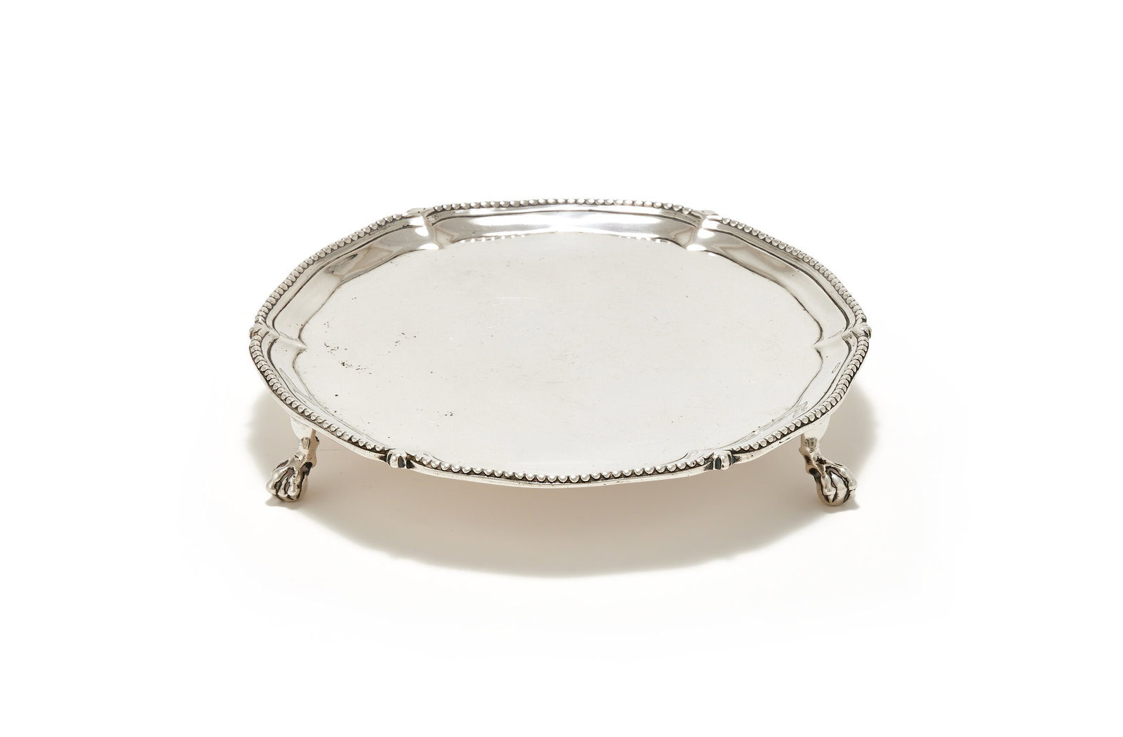 A GEORGE III SILVER SHAPED CIRCULAR WAITER, RICHARD RUGG II, LONDON 1776: A GEORGE III SILVER SHAPED CIRCULAR WAITERRICHARD RUGG II, LONDON 1776With a beaded border and on three ball and claw feet15.5cm diameter225g (7.25 oz)