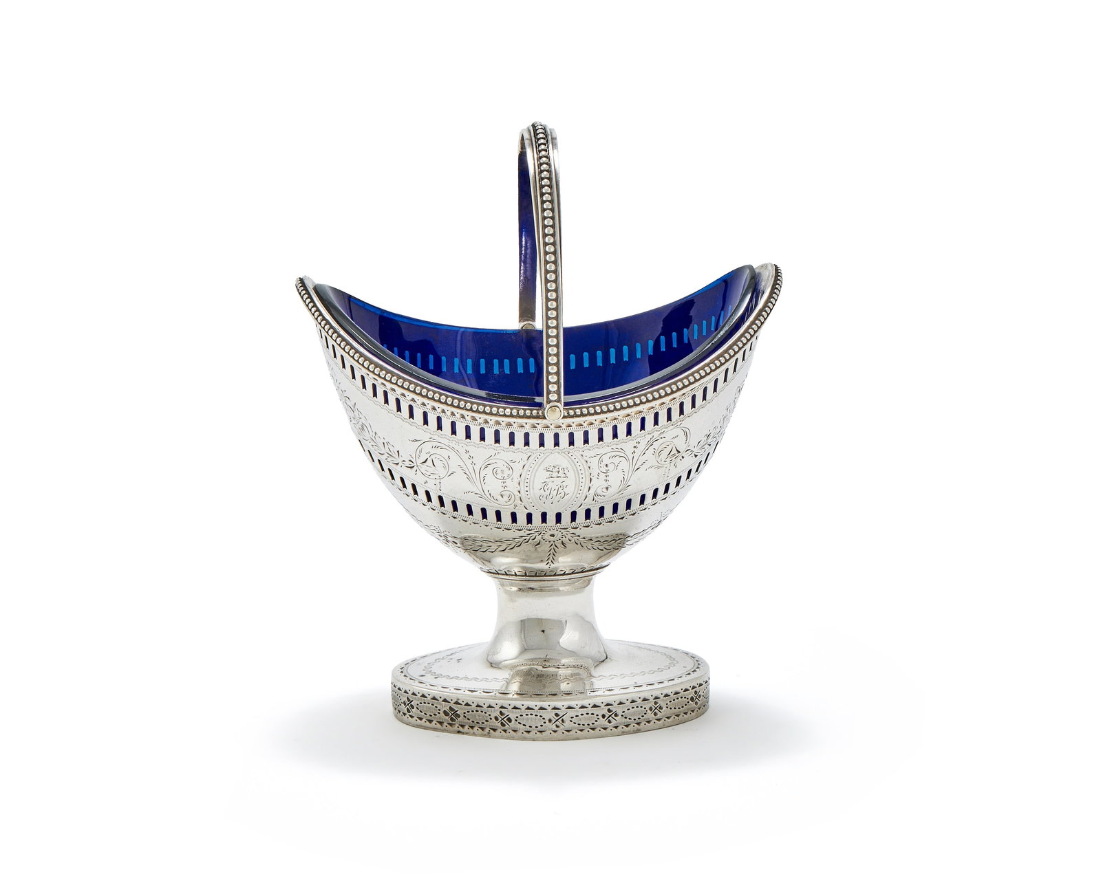 A GEORGE III SILVER SWING HANDLED OVAL PEDESTAL SUGAR BASIN, JOHN WALL, LONDON 1785: A GEORGE III SILVER SWING HANDLED OVAL PEDESTAL SUGAR BASINJOHN WALL, LONDON 1785With a beaded border and swing loop handle, engraved with foliate bands, a crest and a monogram, on an oval pedestal fo