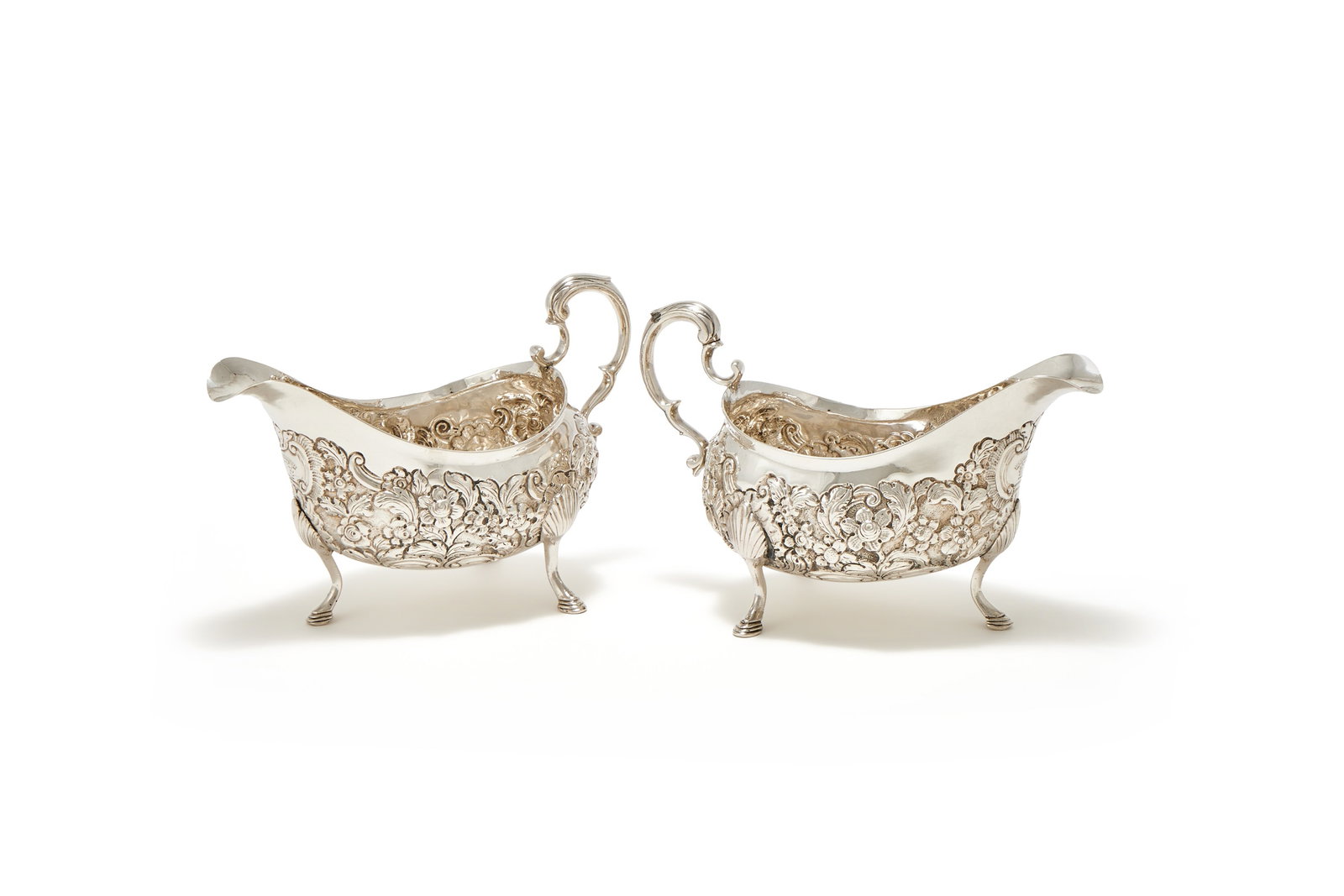 A PAIR OF IRISH PROVINCIAL SILVER OVAL SAUCE BOATS, POSSIBLY BY HENRY DOWENS, LIMERICK CIRCA 1780: A PAIR OF IRISH PROVINCIAL SILVER OVAL SAUCE BOATSPOSSIBLY BY HENRY DOWENS, LIMERICK CIRCA 1780With leaf capped double scroll handles, chased with flowers and C-scrolls, engraved with a crest and PH b