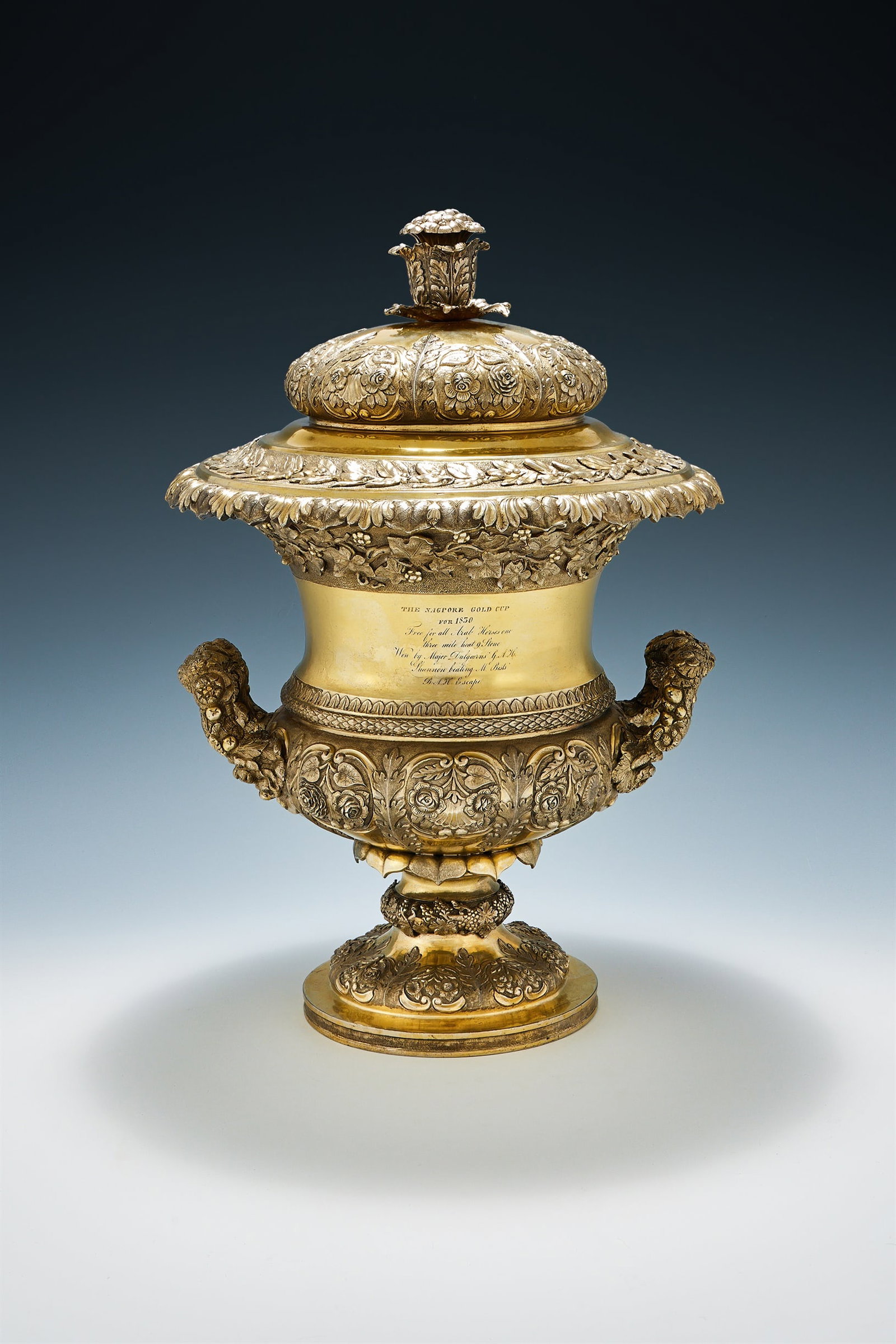 AN INDIAN COLONIAL SILVER GILT TWIN HANDLED TROPHY CUP AND COVER, HAMILTON & CO., CIRCA 1830: AN INDIAN COLONIAL SILVER GILT TWIN HANDLED TROPHY CUP AND COVERHAMILTON & CO., CALCUTTA, CIRCA 1830With a flower finial to the ogee domed cover, chased with flowers, acanthus and bay leaf bands, the 