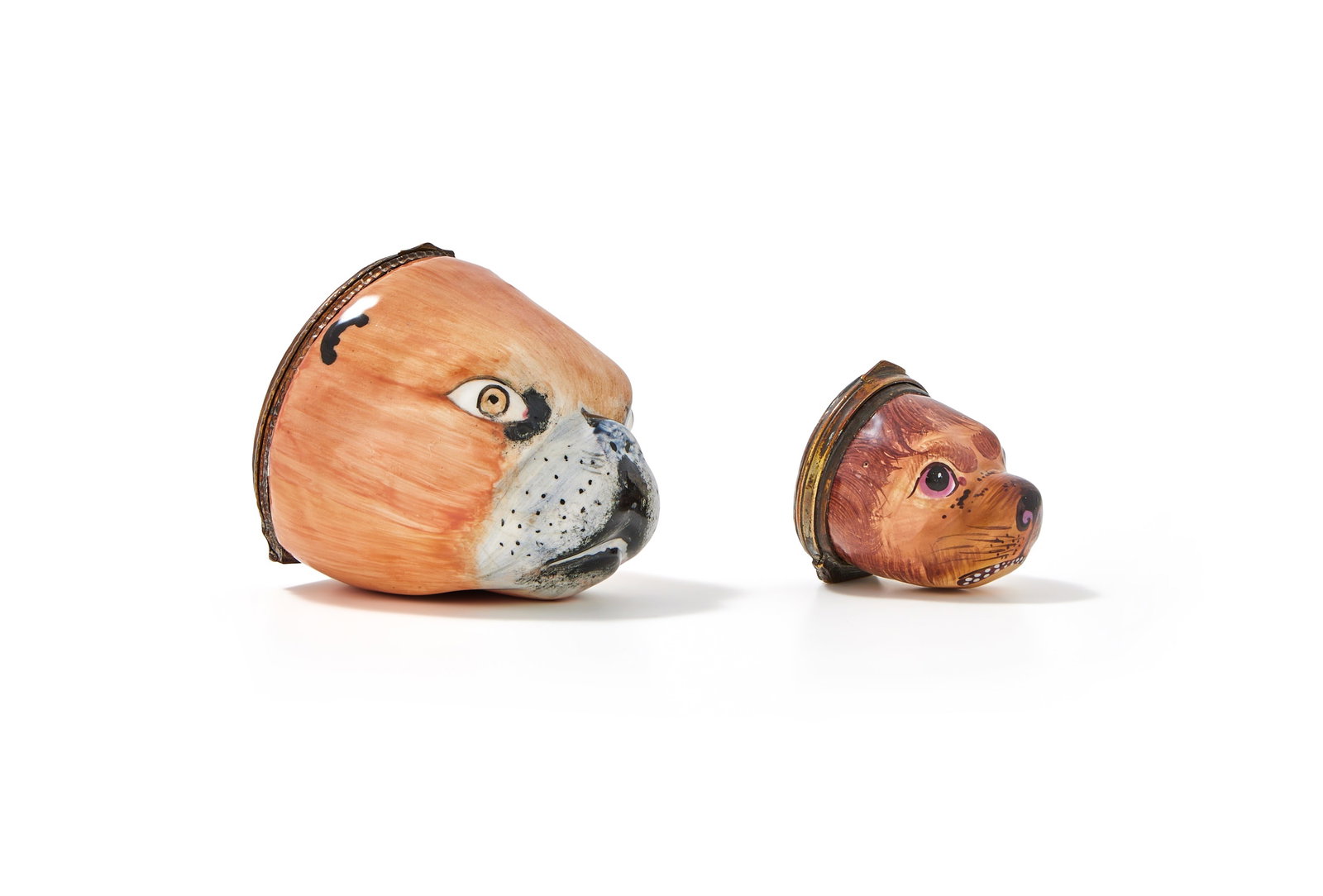 TWO ENAMEL PUG DOG SNUFF BOXES OR BONBONNIERS, LATE 18TH CENTURY: AN ENAMEL PUG DOG SNUFF BOX OR BONBONNIERPROBABLY SOUTH STAFFORDSHIRE OR GERMAN, LATE 18TH CENTURYModelled as the head of a pug, its coat apricot, the lid painted with a woman and her dog5cm diameterT