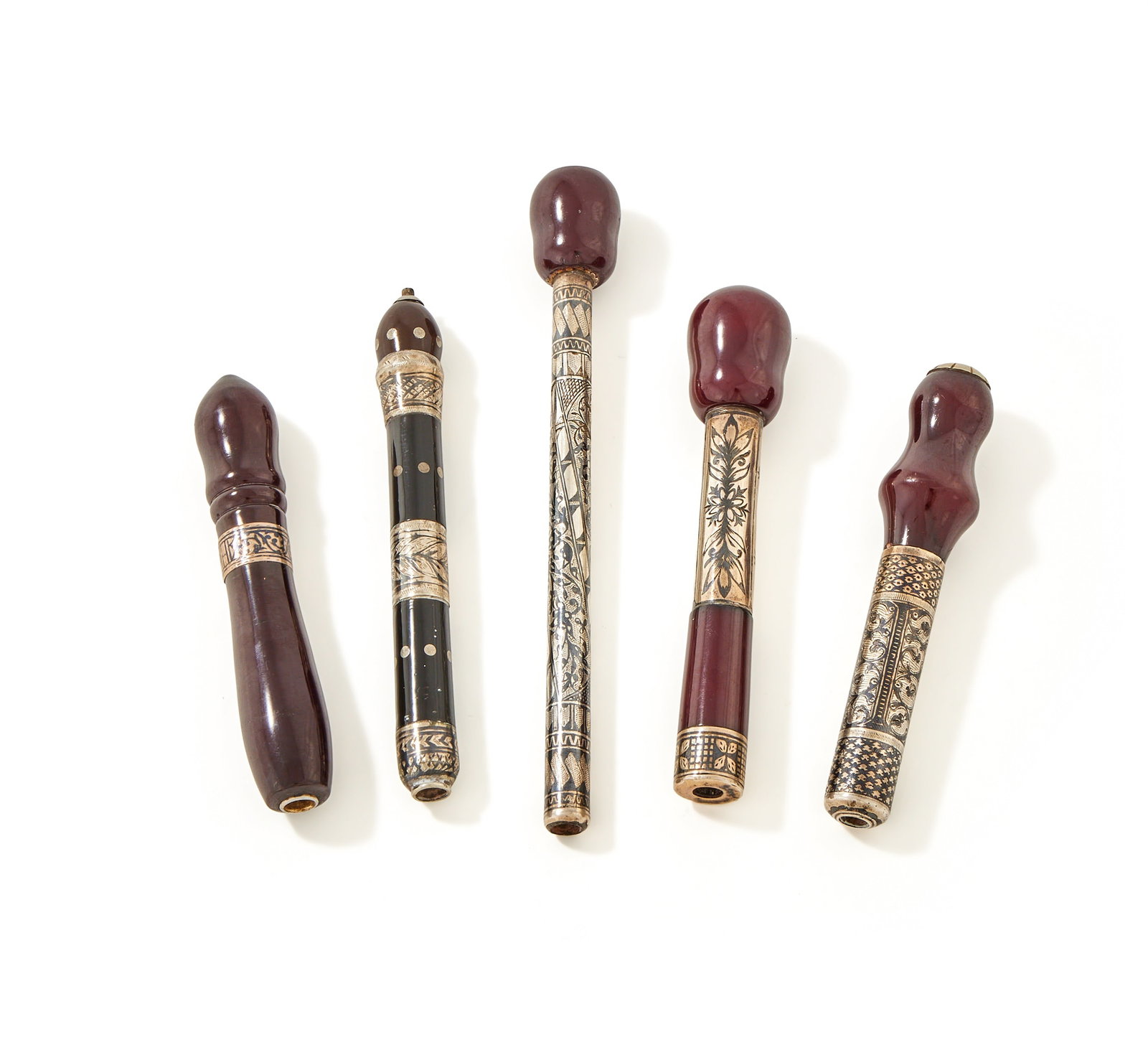 FIVE OTTOMAN CIGARETTE HOLDERS, TURKEY, 19TH CENTURY: FIVE OTTOMAN CIGARETTE HOLDERS TURKEY, 19TH CENTURYComprising:A SILVER, NIELLO AND PRESSED AMBER CIGARETTE HOLDERUNMARKEDWith foliate and geometric decoration, and a pressed amber pommel19.5cm longA S