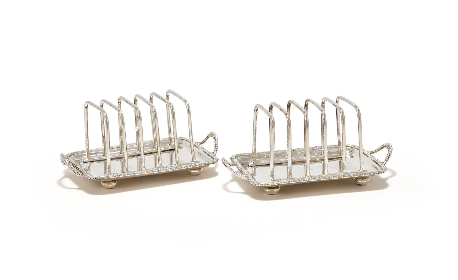A PAIR OF EDWARDIAN SILVER FIVE DIVISION TOAST RACKS, LAMBERT & CO., LONDON 1908: A PAIR OF EDWARDIAN SILVER FIVE DIVISION TOAST RACKSLAMBERT & CO., LONDON 1908With gadrooned borders and twin loop handles, on four bun feet15cm long486g (15.65 oz)
