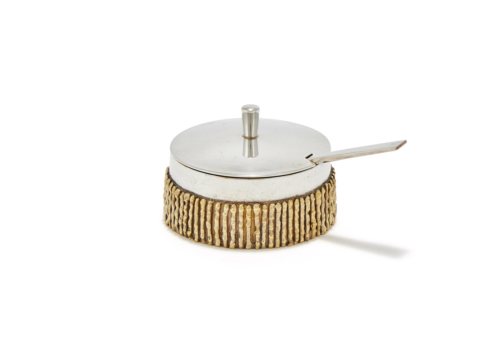 STUART DEVLIN, A SILVER AND SILVER GILT MUSTARD POT AND SPOON, LONDON 1966: STUART DEVLINA SILVER AND SILVER GILT MUSTARD POT AND SPOON, LONDON 1966With a tapering finial to the slightly domed cover, the body with a silver gilt textured band, the spoon with a tapering handleT