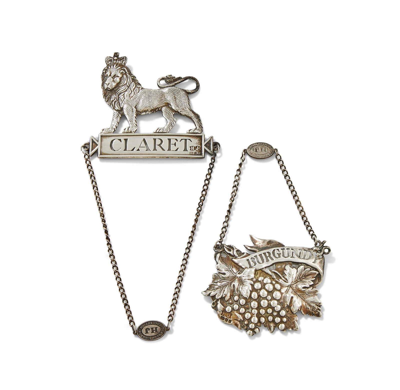 TWO SILVER DECANTER LABELS: A SILVER DECANTER LABELHUGH JOHNSON, LONDON 1986With a crowned lion above a rectangular panel, pierced Claret8cm longTogether with:A SILVER DECANTER LABELHUGH JOHNSON, LONDON 1985Chased with grapes an