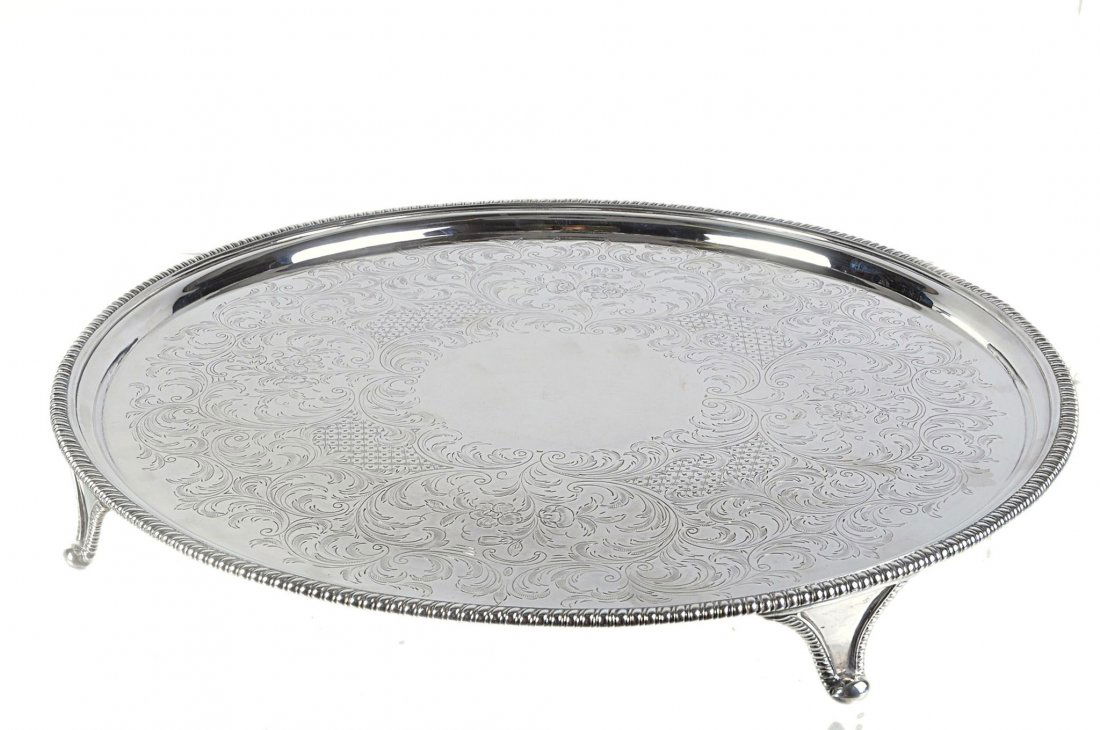 A George III silver salver by John Edwards III, Lo: A George III silver salver by John Edwards III, London 1794, with a gadrooned border, later engraved with scrolls and on four gadrooned and pad feet, 43cm diameter, 60.85 oz