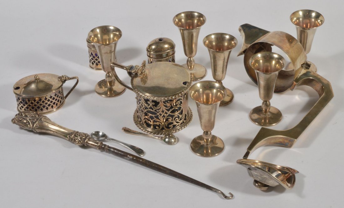An Edwardian silver mustard by Charles Stuart Harris,: An Edwardian silver mustard by Charles Stuart Harris, London 1901, the flat cover with a shell thumb piece, a scroll handle, knurled borders and a pierced body, 9.4cm long, with a blue glass liner; a