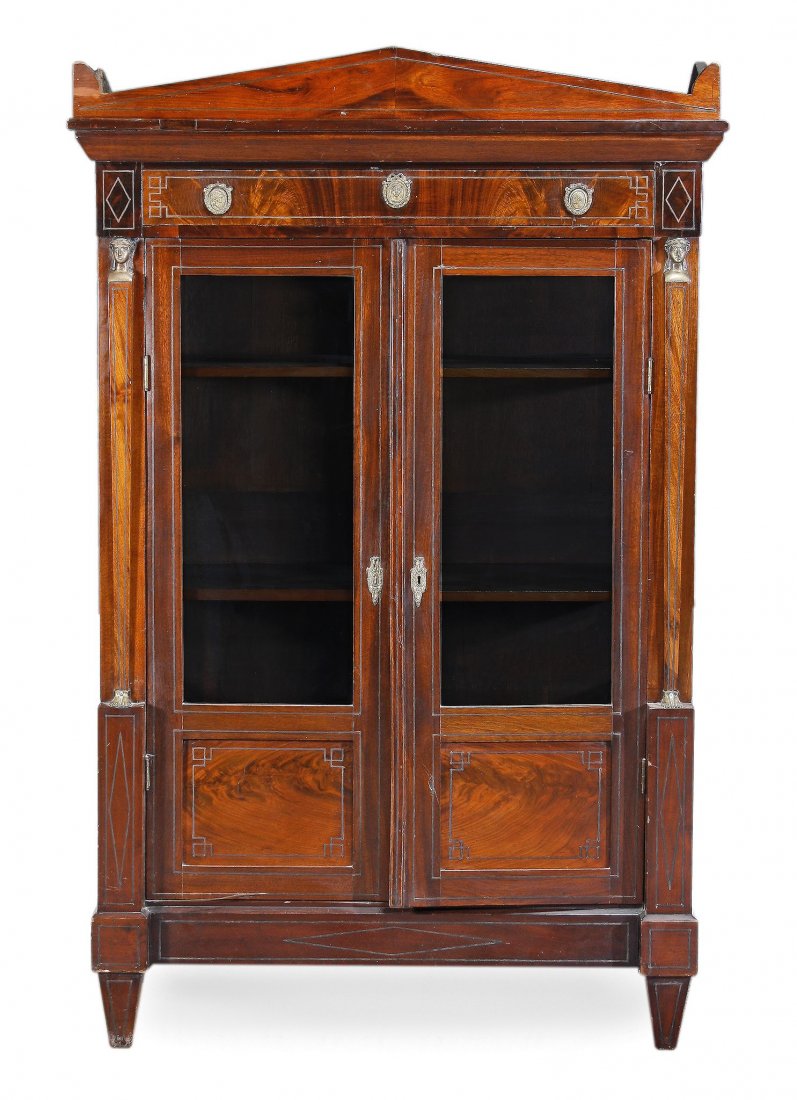 A Regency mahogany and metal mounted display cabinet ,: A Regency mahogany and metal mounted display cabinet , circa 1815, with an arched cornice, above a frieze drawer, the handles with embossed female masks, above a pair of glazed panelled doors flanked 