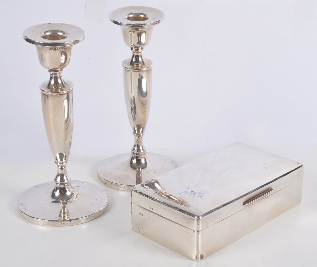A pair of silver candlesticks by Henry Clifford Davis,: A pair of silver candlesticks by Henry Clifford Davis, Birmingham 1921, with circular sconces, bell shaped capitals, tapering stems and on circular bases, 19.5cm high, loaded; and a rectangular cigare