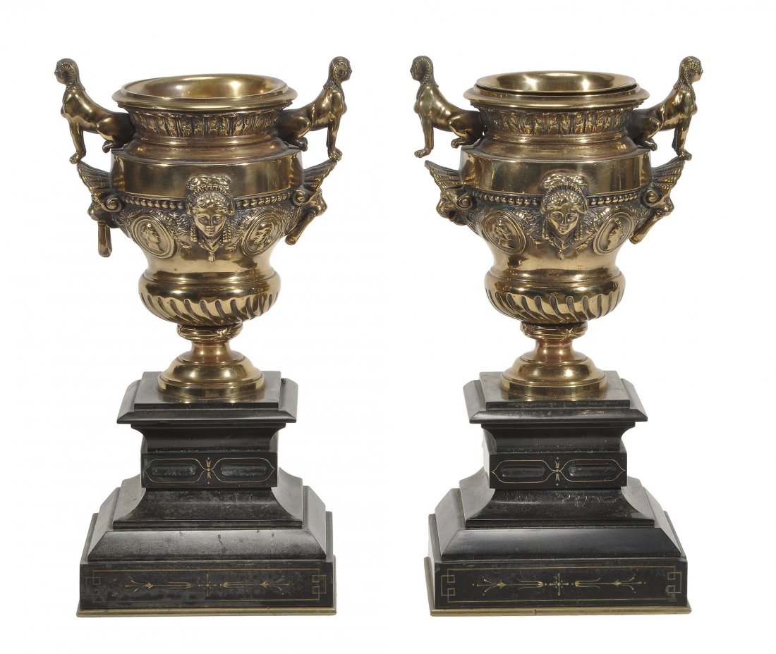 A pair of French bronze and marmo nero Belgio mounted: A pair of French bronze and marmo nero Belgio mounted urns, last quarter 19th century, each with twin seated sphinxes above lion's mask and ring handles, the bodies with maiden's masks flanked by prof