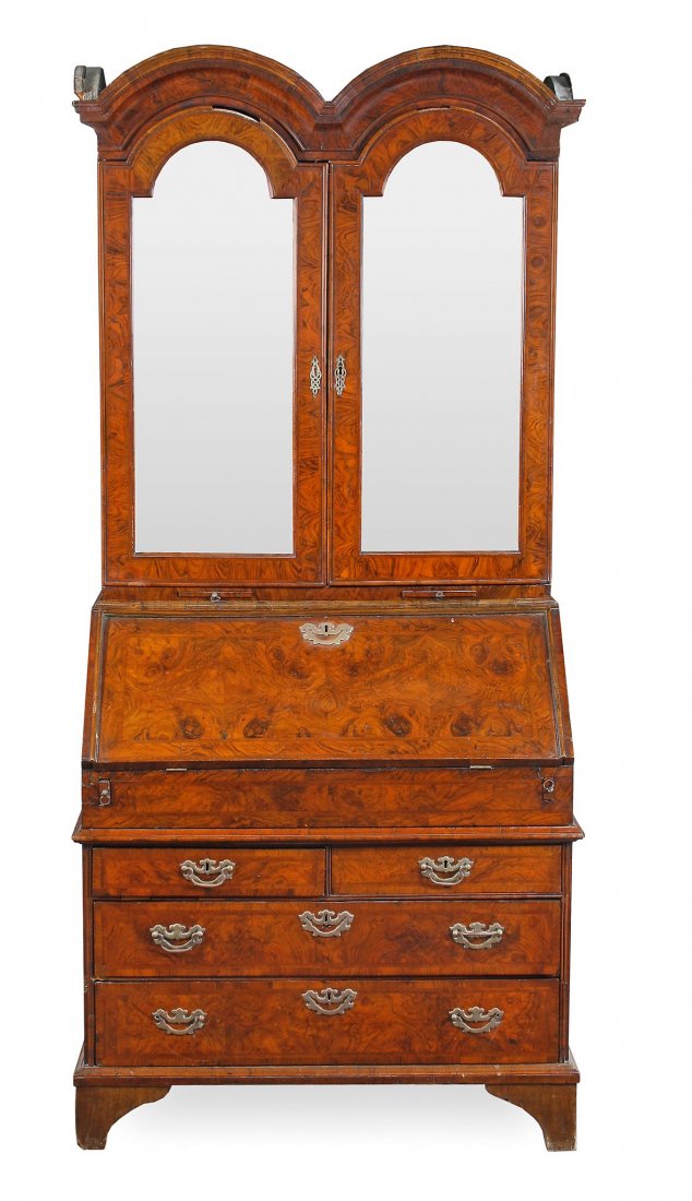 A George II walnut double dome bureau bookcase, circa: A George II walnut double dome bureau bookcase, circa 1740, the moulded cornice above a pair of mirror panelled doors opening to shelves, the base with a hinged fall opening to small drawers, pigeon h
