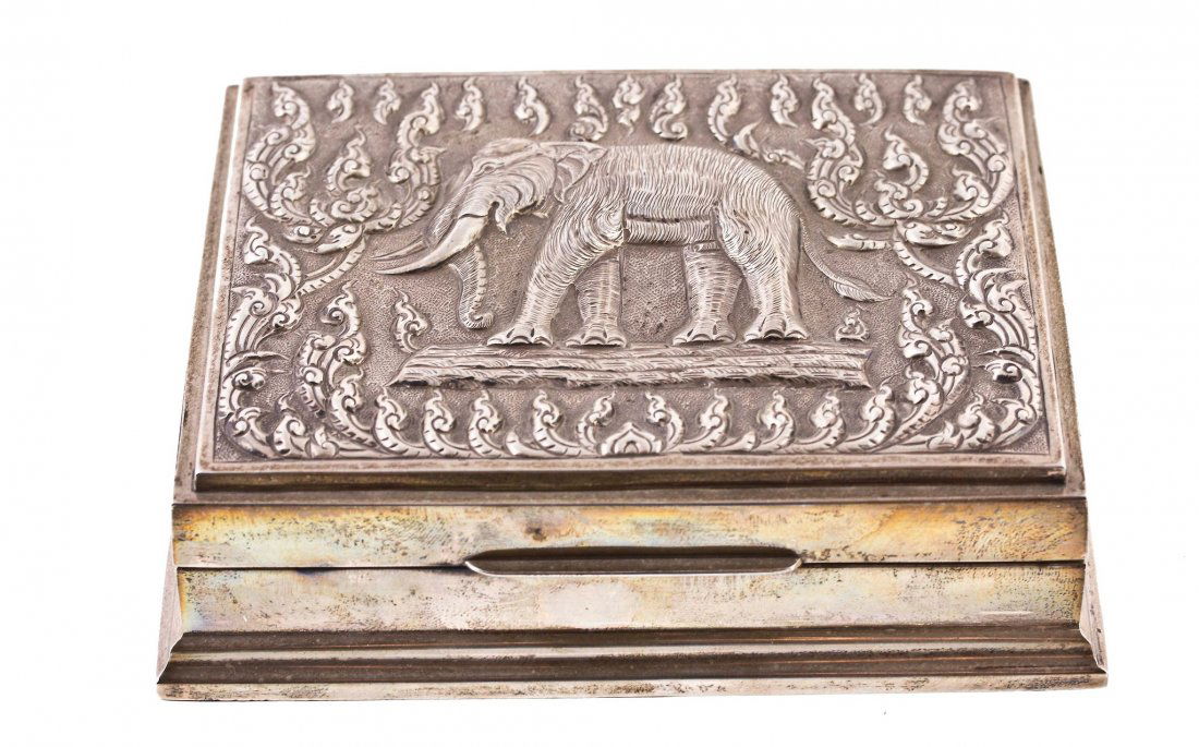 A Thai silver coloured box, stamped 'Sterling': A Thai silver coloured box, stamped 'Sterling', the hinged cover embossed with an elephant and foliate decoration, 14cm long, with a wood liner