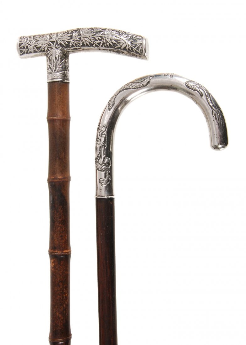 An Anglo-Chinese white metal mounted stained hardwood: An Anglo-Chinese white metal mounted stained hardwood walking stick, circa1900, the crook grip decorated with dragons and other motifs, the shaft with brass ferrule, 86cm high; and an Oriental white m