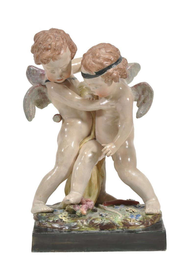 A large Staffordshire pearlware group of two wrestling: A large Staffordshire pearlware group of two wrestling putti, circa 1825, on a flower-encrusted mound and a black rectangular base, 41.5cm high