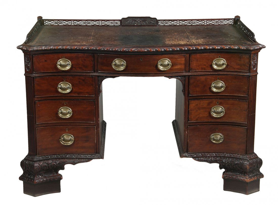 An Edwardian mahogany serpentine fronted desk, in: An Edwardian mahogany serpentine fronted desk, in George III style , circa 1910, in the manner of Thomas Chippendale, with a pierced gallery with central rear panel carved with ribbon and scrolling le