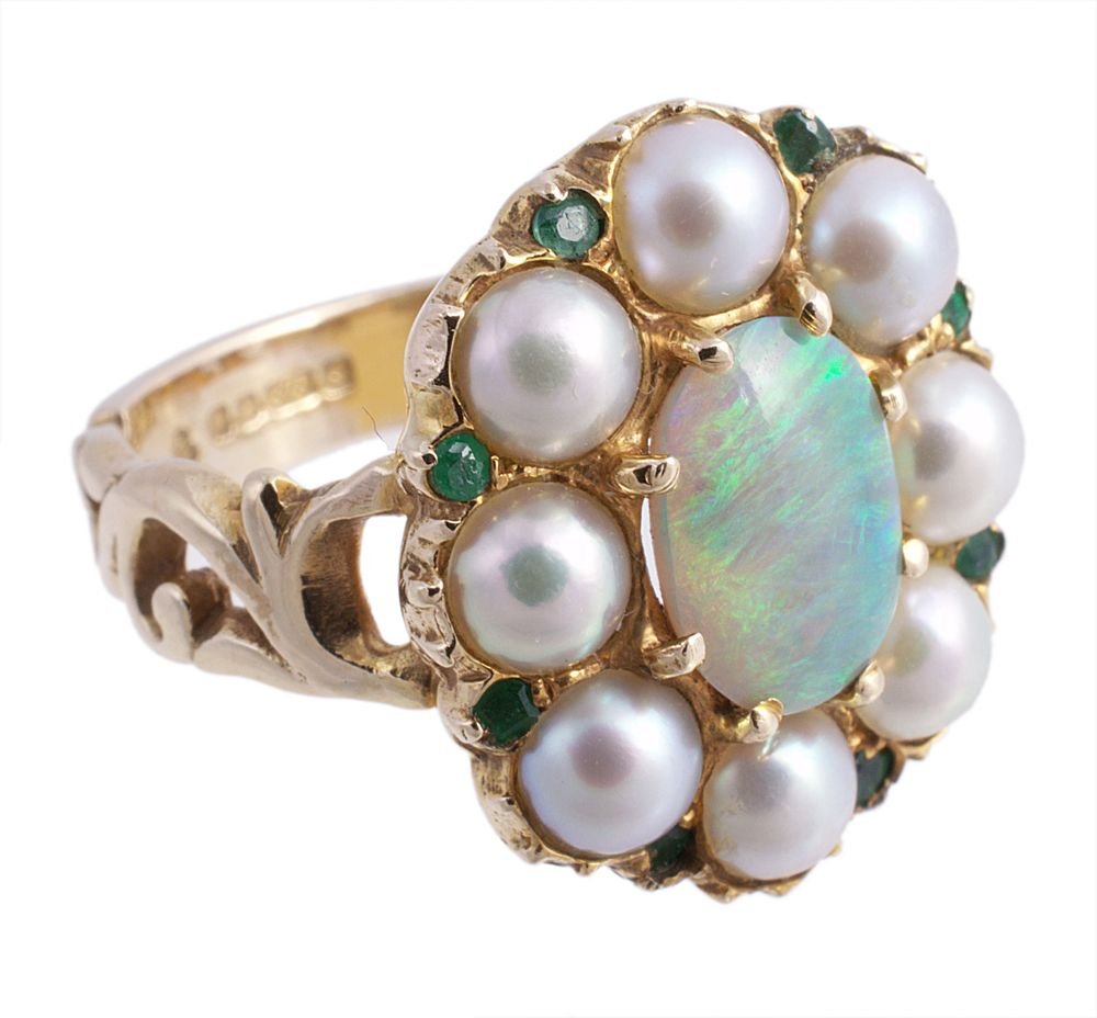 A 9 carat gold opal, half pearl and emerald ring: A 9 carat gold opal, half pearl and emerald ring, the central oval cabochon opal within a surround of half pearls and circular cut emeralds, stamped 375 and hallmarked for Sheffield 1990, finger size