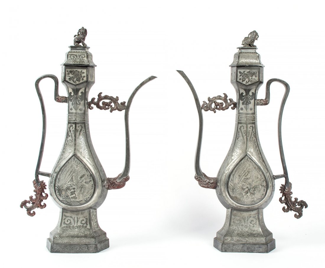 A pair of pewter ewers, 19th century , of Middle: A pair of pewter ewers, 19th century , of Middle Eastern metalwork form with thin, curving handle and spout, finely cast with flowers, scrollwork and phoenixes, the covers surmounted by knobs shaped a
