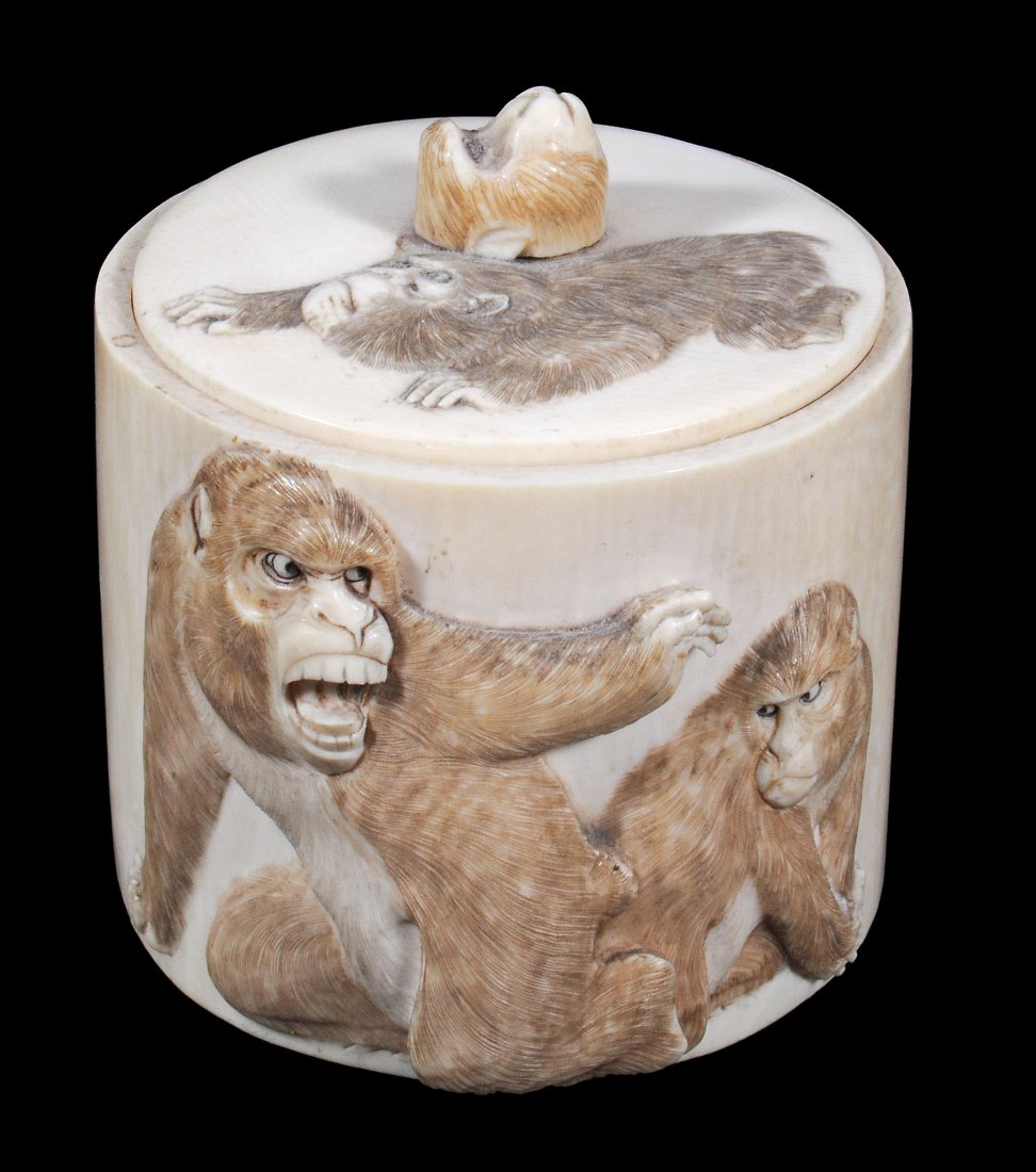 A circular Japanese ivory box and cover , the sides: A circular Japanese ivory box and cover , the sides carved in relief with monkeys, 8cm high