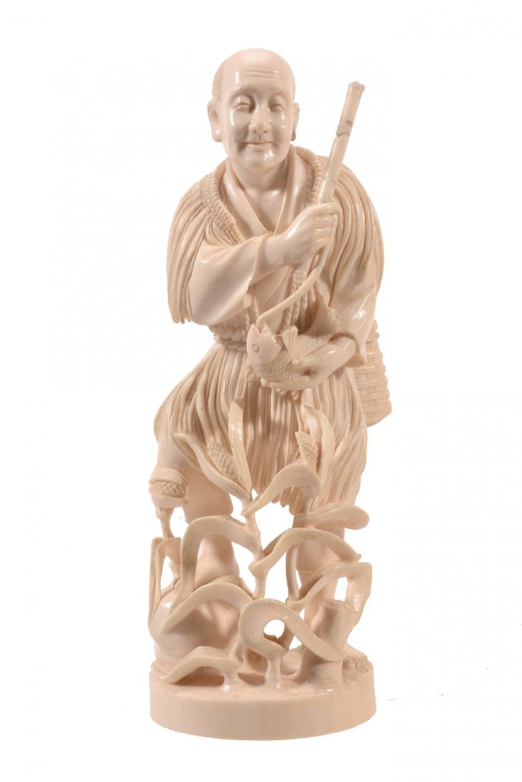 An Ivory Okimono of a Fisherman , he stands with his: An Ivory Okimono of a Fisherman , he stands with his foot on a rocky outcrop amids maize plants, he cradles a fish in one hand which dangles from the bamboo fishing rod he holds in the other, all on a