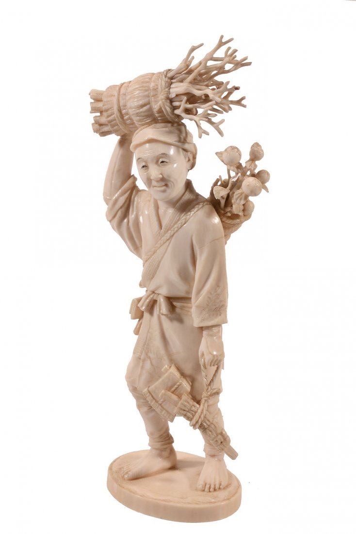 An Ivory Okimono of a Woodcutter, the man walks his saw: An Ivory Okimono of a Woodcutter, the man walks his saw and axe hanging from his left hand, a bundle of fruiting branches strung across his back and a large bundle of faggots carried on his head, sign