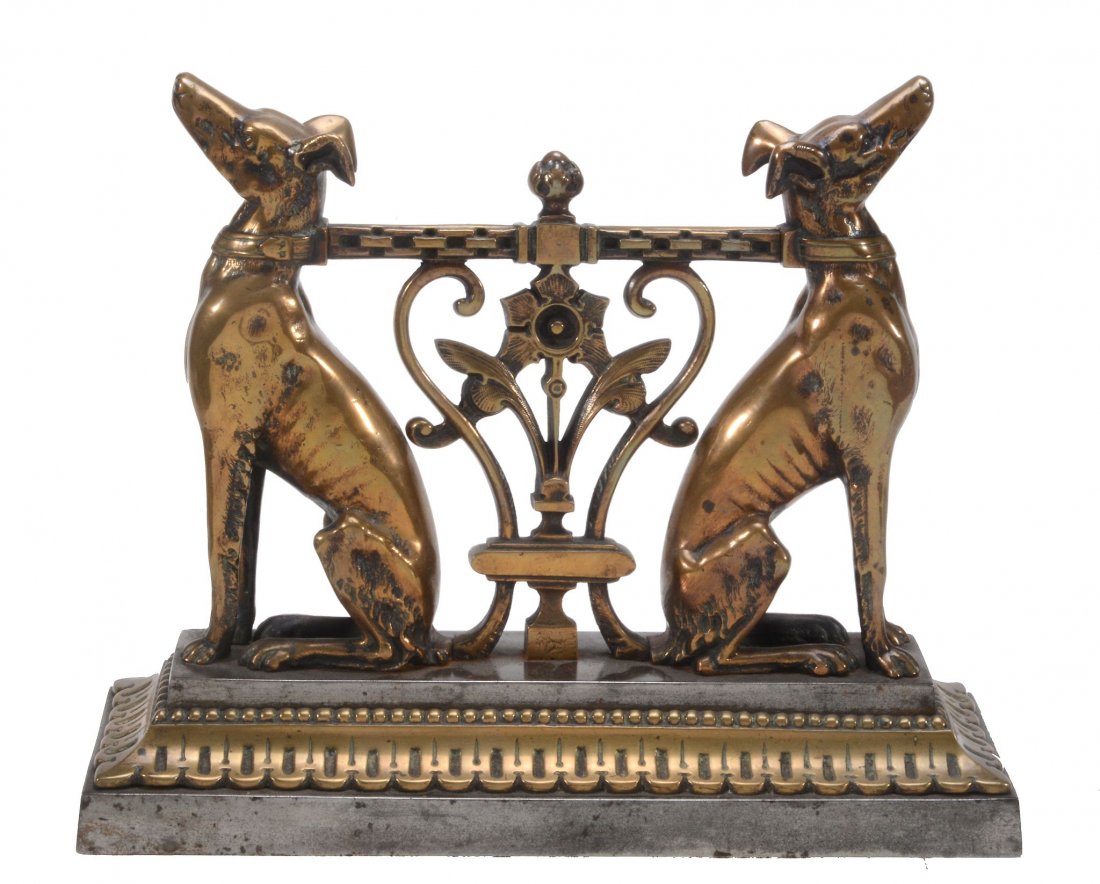A Victorian brass and steel mounted door porter or fire: A Victorian brass and steel mounted door porter or fire tool rest, last quarter 19th century, cast as twin adorsed seated hounds with a bar cast as a stylised chain running between them, above a scrol