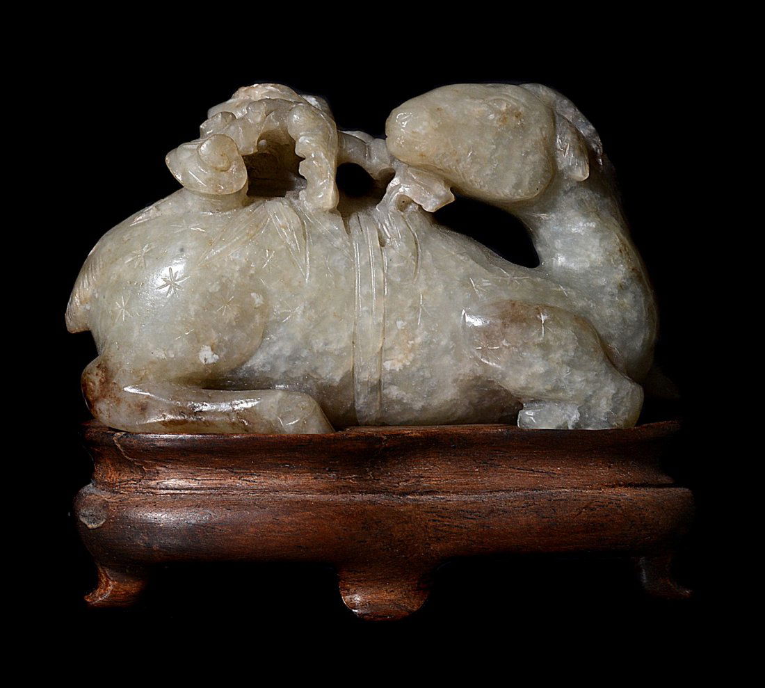 A Chinese celadon jade deer , Qing, with russet and: A Chinese celadon jade deer , Qing, with russet and 'mutton fat' inclusions, recumbent with head turned back and with a flowering peach branch in its mouth, approximately 6.8cm long x 3.8cm highest po