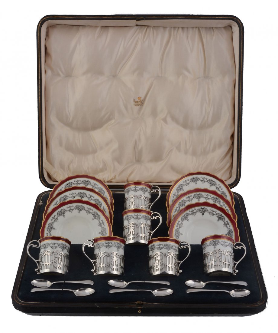 A cased set of six Aynsley coffee cans and saucers with: A cased set of six Aynsley coffee cans and saucers with silver mounted cup holders by Cooper Brothers & Sons Ltd., Sheffield 1918, with scroll handles, pierced bodies with a foliate swag band, 6cm (2 