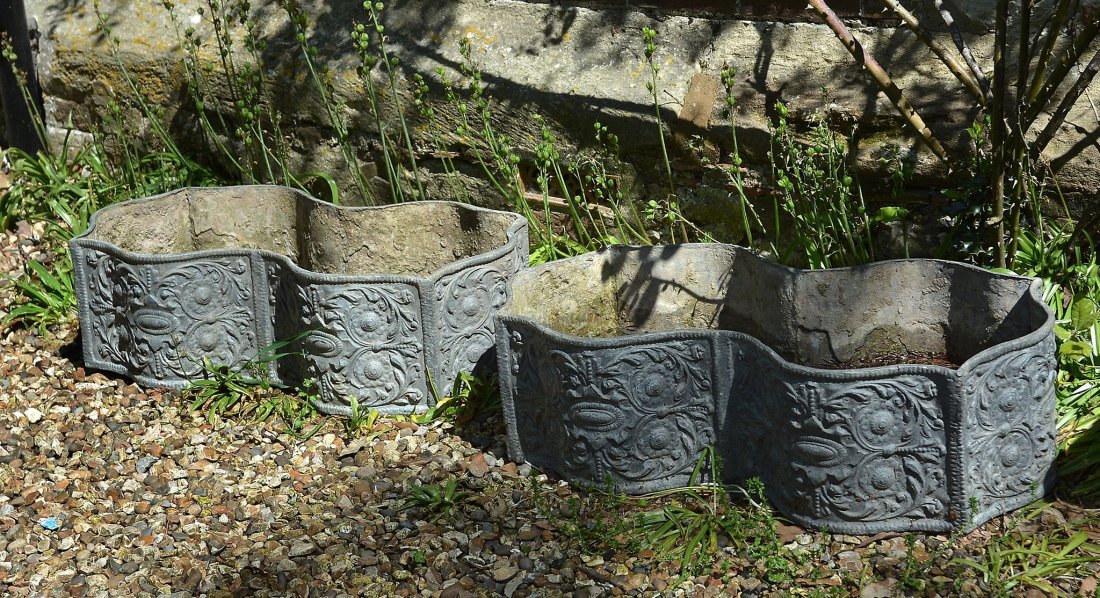 A pair of lead garden planters or window boxes, early: A pair of lead garden planters or window boxes, early 20th century, of loosely rectangular form with serpentine sides, relief cast with scrolling foliage overall, 22cm high, 73cm long, 40cm wide