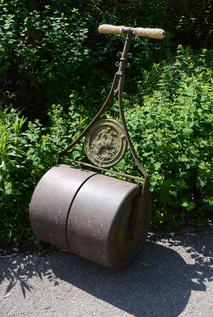 A late Victorian or Edwardian cast and wrought iron: A late Victorian or Edwardian cast and wrought iron garden roller, circa 1900, the cylindrical roller cast in two sections, beneath a relief cast roundel depicting St George and the Dragon, the handle