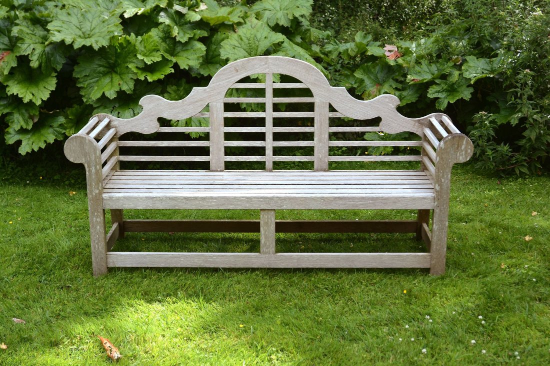 A teak garden seat in the manner of designs by Lutyens,: A teak garden seat in the manner of designs by Lutyens, of recent manufacture, the 'Sissinghurst' by Barlow Tyrie, the arched and serpentine backrests above slatted seats and outscrolled arms, 107cm h