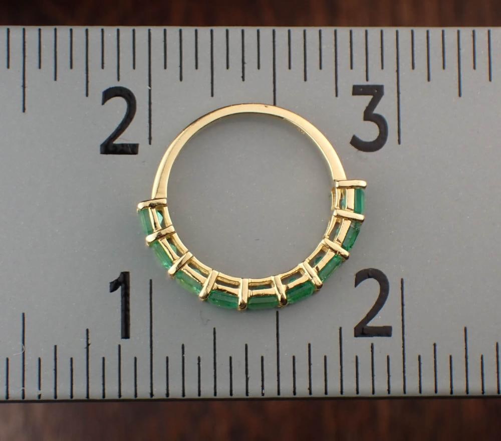 EMERALD AND FOURTEEN KARAT YELLOW GOLD RING: EMERALD AND FOURTEEN KARAT YELLOW GOLD RING, set with nine emerald-cut emeralds together weighing 2.10 grams. The ring weighs 1.9 grams and is stamped "585". Ring size: 6.