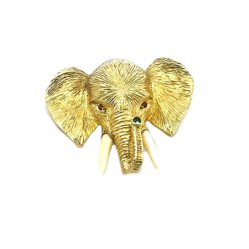 Sterle Paris Elephant Gold Brooch 18k Yellow Gemstones 3D Textured Style: This is an adorable pendant by Sterle Paris, it features an elephant head with detailed and fine fur textured finish, the elephant's trunk is curled up and its eyes are red gemstones with green stone