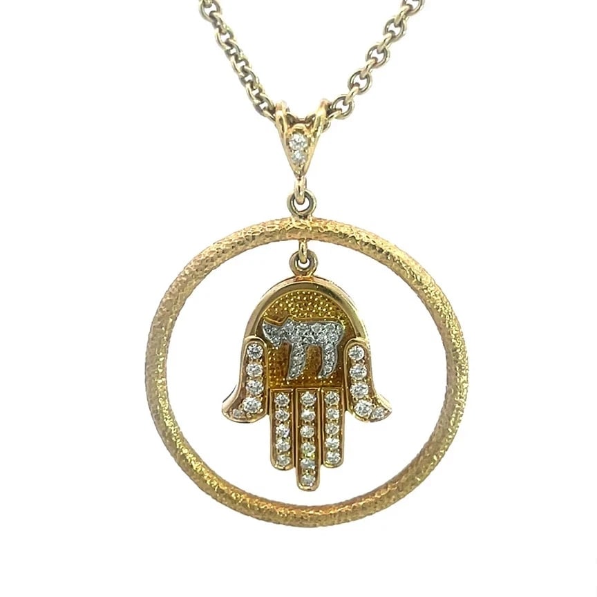 Diamond Gold Hamsa Chai Necklace 18k Yellow Circle Dangle Pendant w/ Chain: The Diamond Gold Hamsa with Chai Pendant dangles in a textured large ring attached to a diamond decorated bail. The hand has round white diamonds and a small chai in white gold is at the top of the ha