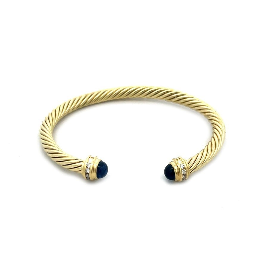 David Yurman Diamond Gold Cuff Bracelet Gemstone Cable Band: This is an elegant cuff bracelet by David Yurman from the Cable Classics Collection. It is a luxurious and elegant piece of fine jewelry. with cabochon blue gemstone knobs accented with diamonds on ea