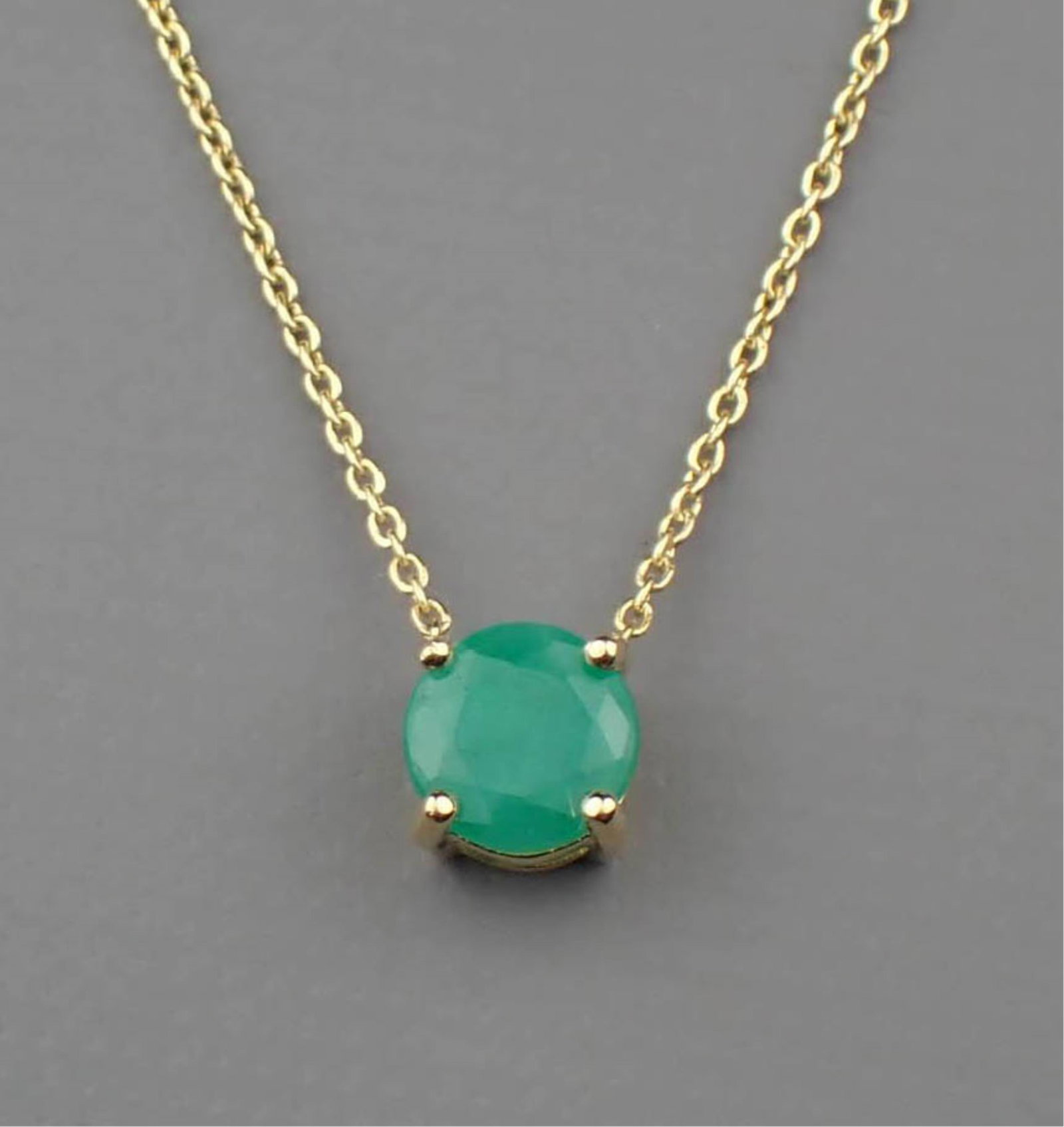 EMERALD & 14K GOLD SOLITAIRE NECKLACE: EMERALD & 14K GOLD SOLITAIRE NECKLACE:with an adjustable length yellow gold cable chain secured to a 4-prong yellow gold pendant set with a round-cut emerald weighing approximately 0.75 ct. The