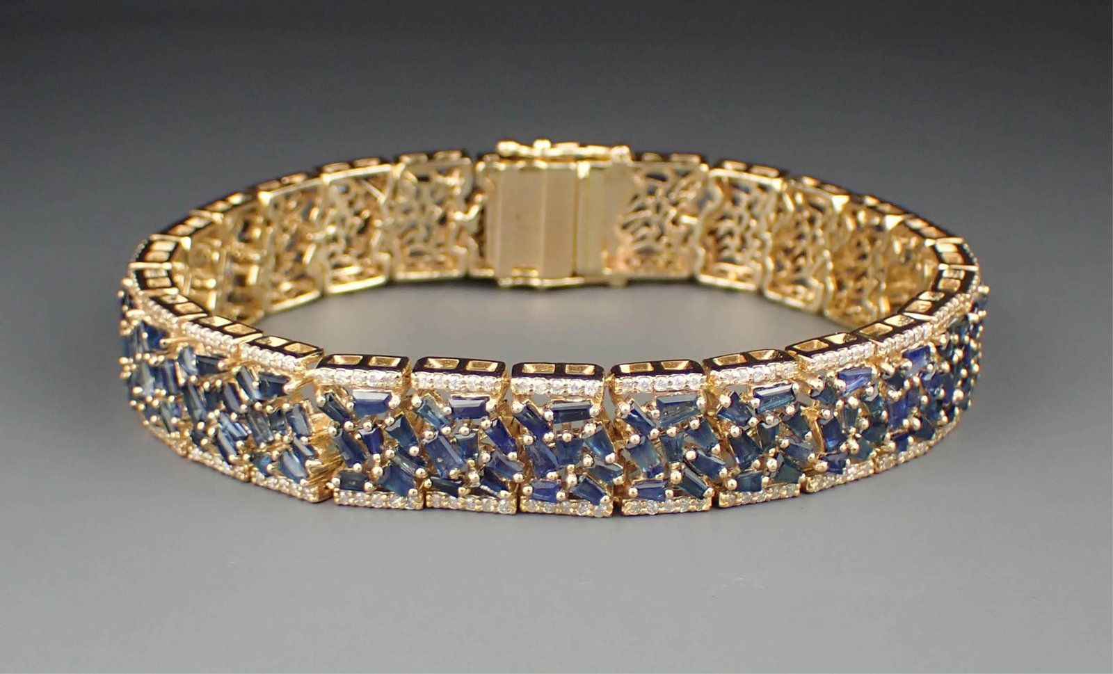 SAPPHIRE, DIAMOND & 14K YELLOW GOLD BRACELET: SAPPHIRE, DIAMOND & 14K YELLOW GOLD BRACELET:7-1/4 inch length set with 208 baguette-cut sapphires weighing approximately 11.80 cttw, and 260 round-cut diamonds weighing approximately 1.90 cttw. The b