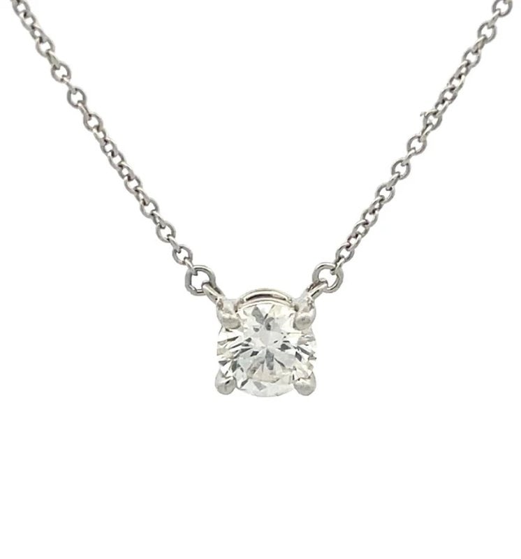 Tiffany & Co. Diamond Solitaire Pendant Platinum Necklace Box & Paper: The product is a stunning Tiffany & Co. Diamond Solitaire Pendant Necklace in Platinum, featuring a round brilliant white diamond with a total carat weight of 0.63 in a basket setting. The necklace ha
