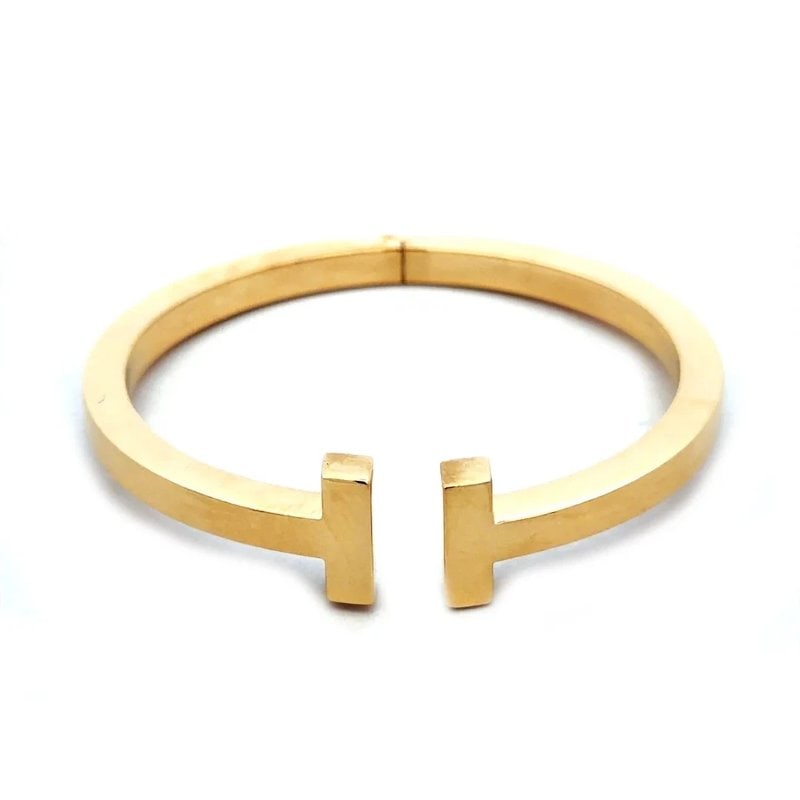 Tiffany T Square Gold Bracelet 18k Yellow Hinged Cuff Style large Model: This chic fashionable bracelet is by Tiffany & Co. from the celebrated Tiffany T Square Collection. It is composed of 18k yellow gold with a polished finish featuring a bold, architectural graphic rep