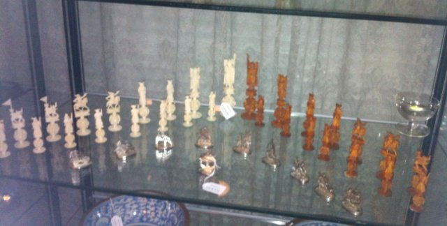 CHINESE CARVED IVORY CHESS SET: CHINESE CARVED IVORY CHESS SET EACH PIECE IS INTRICATELY CARVED IVORY WITH A FIGURAL SURMOUNT AND A PUZZLE BALL TERMINAL. OPPOSING PIECES ARE TEA STAINED IVORY. ALL ENCASED IN LATER WOODEN CHESS TOP B