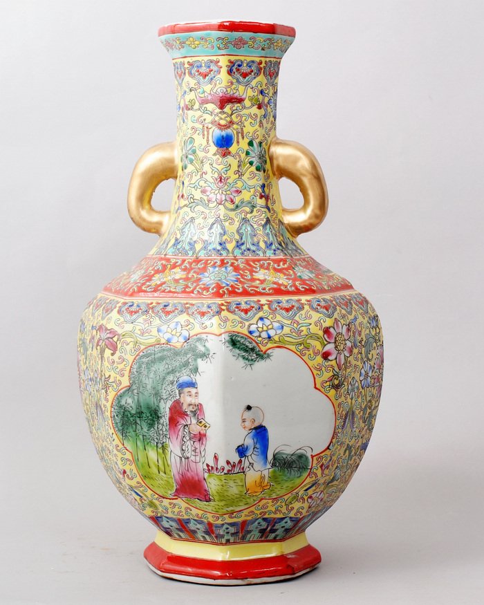 CHINESE FAMILLE ROSE PORCELAIN VASE: THE VASE WITH TWO GOLD HANDLES, YELLOW BASE,FLORAL AND BATS ARE RAISED. PICTURES WITH TWO FIGURES UNDER THE TREE IN FRONT & BACK. SIX CHARACTER GREAT QIANLONG PRODUCTION IN UNDERGLAZE BLUE ON BOTTOM,H