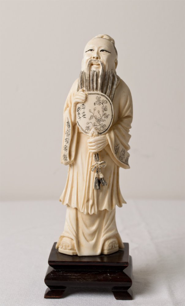 A FINE CHINESE IVORY CARVING ON STAND: FINELY CARVED TO DEPICT THE FAMOUS CHINESE MILITARY ADVISER NAMED "ZHU,GELIANG",HOLDING HIS FAN, MOUNTED ON A CARVED WOOD STAND.6.5"H.