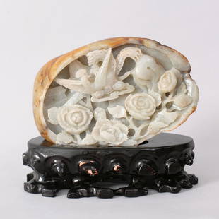 1086: A FINE CHINESE CARVED HETIAN JADE BOULDER: JADE WITH RUSSET SKIN, CARVED TO DEPICT A FLYING PHOENIX AMONG FLORAL AND A HOUSE. ATTACHED TO CARVED WOODEN STAND