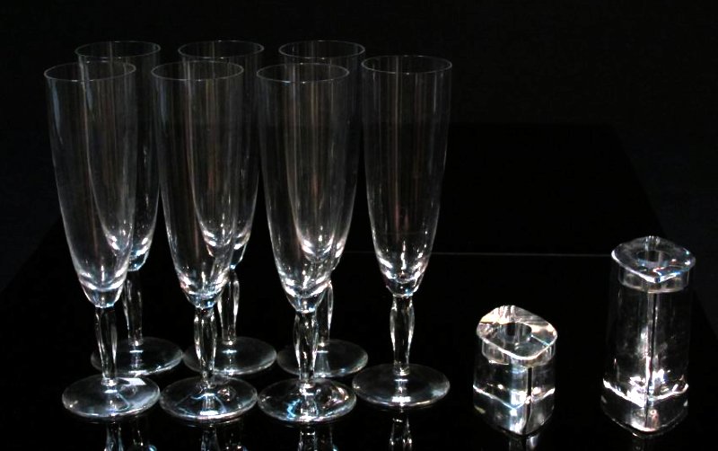 DAUM CRYSTAL CHAMPAGNE FLUTES & CANDLESTICKS: Seven Daum crystal champagne flutes (8") sold together with two modern Daum crystal candlesticks. (4" & 2"). All engraved Daum.