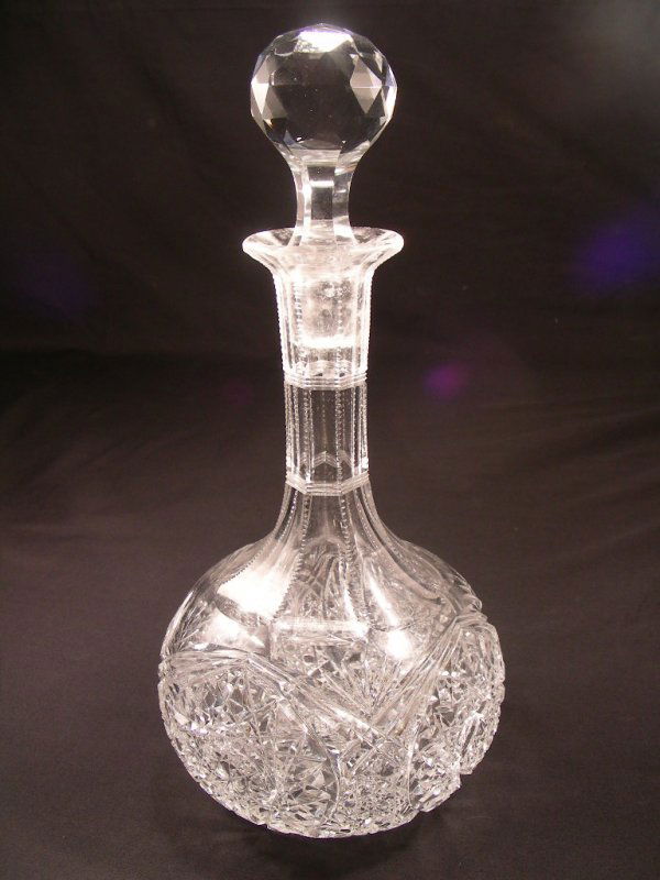 CUT GLASS CRYSTAL DECANTER: All over hobstars and alternating cane facet stopper. Rayed base with notched prism neck. Minor staining inside. No chips or cracks. Measures 7 3/4" tall x 4 1/4" wide.