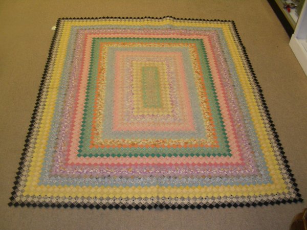 ANTIQUE HAND MADE QUILT SUNSHINE AND SHADOW: Measures 90" long x 75" wide. Pastel 1" diamonds sewn in block form with black diamond edging. Reverse in yellow backing. Beautiful quilt No rips or tears. Few discoloration spots on back side.