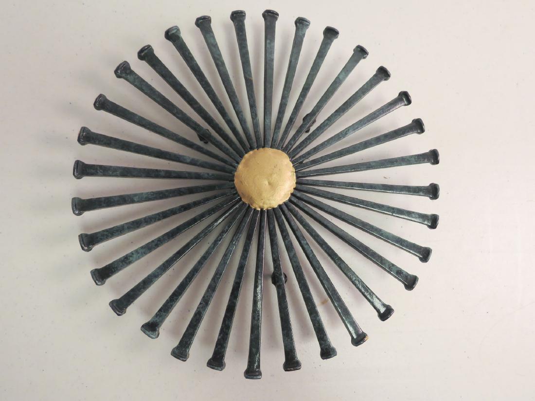 BRUTILIST NAIL ART TRIVET: Brutilist nail art trivet in a starburst pattern with verdigris patinated nails and a gilded center. Signed Ron Schuldt. Measures 9 3/4" wide and stands approximately 1/2" tall. Good condition.