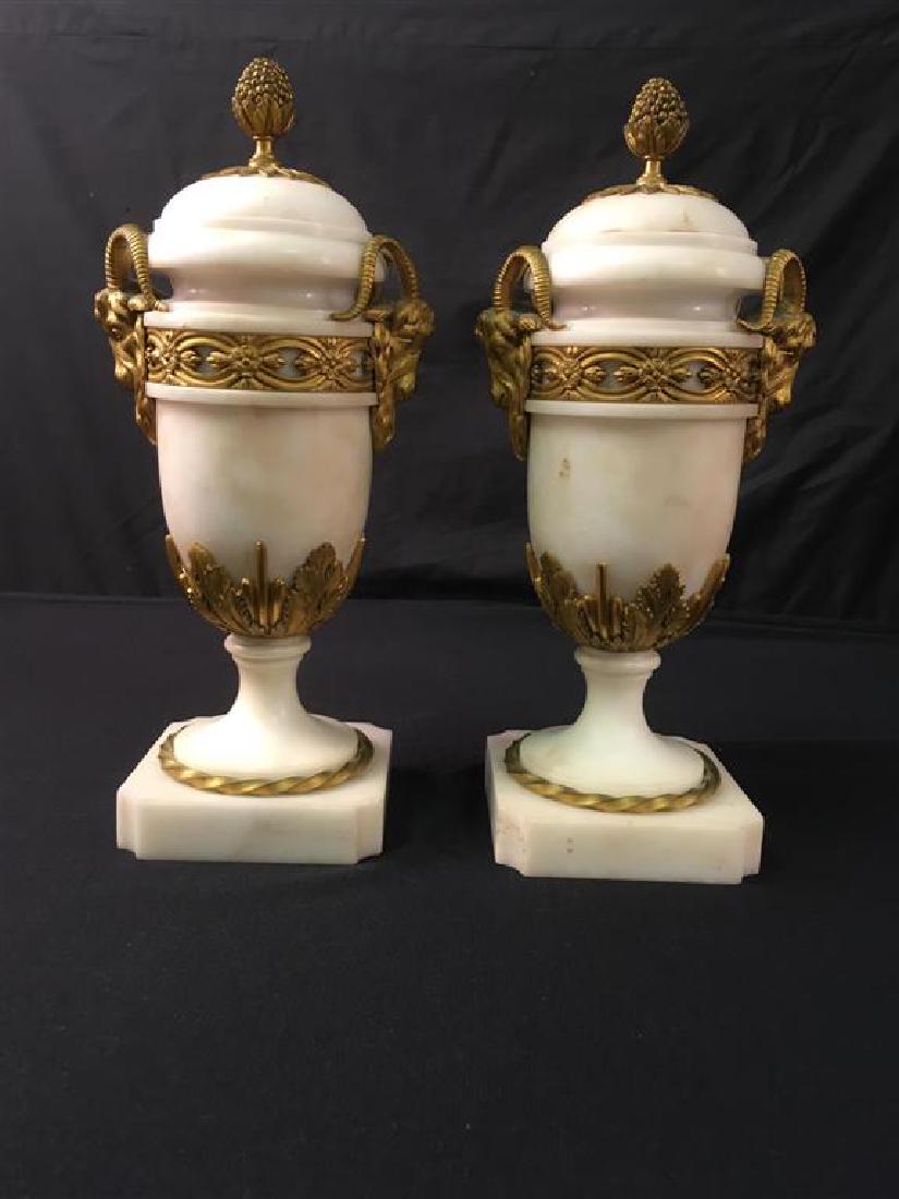 PAIR ALABASTER & ORMOLU URNS W/ RAM'S HEADS: Matched set of two alabaster covered urns with gilded bronze floral, leaf, and ram's head embellishments and gilt metal linings. Each measures 12" tall with lid, and 9.5" x 5" without lids. No apparen
