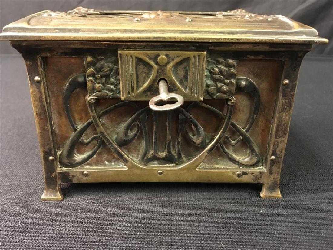 ART NOUVEAU FOOTED BRONZE BOX: Art Nouveau footed bronze box measuring 4.75" tall x 5.75" wide and 4" deep. Remains of yellow fabric lining inside. Condition: wear to fabric lining, lock includes key and turns, but does not lock bo
