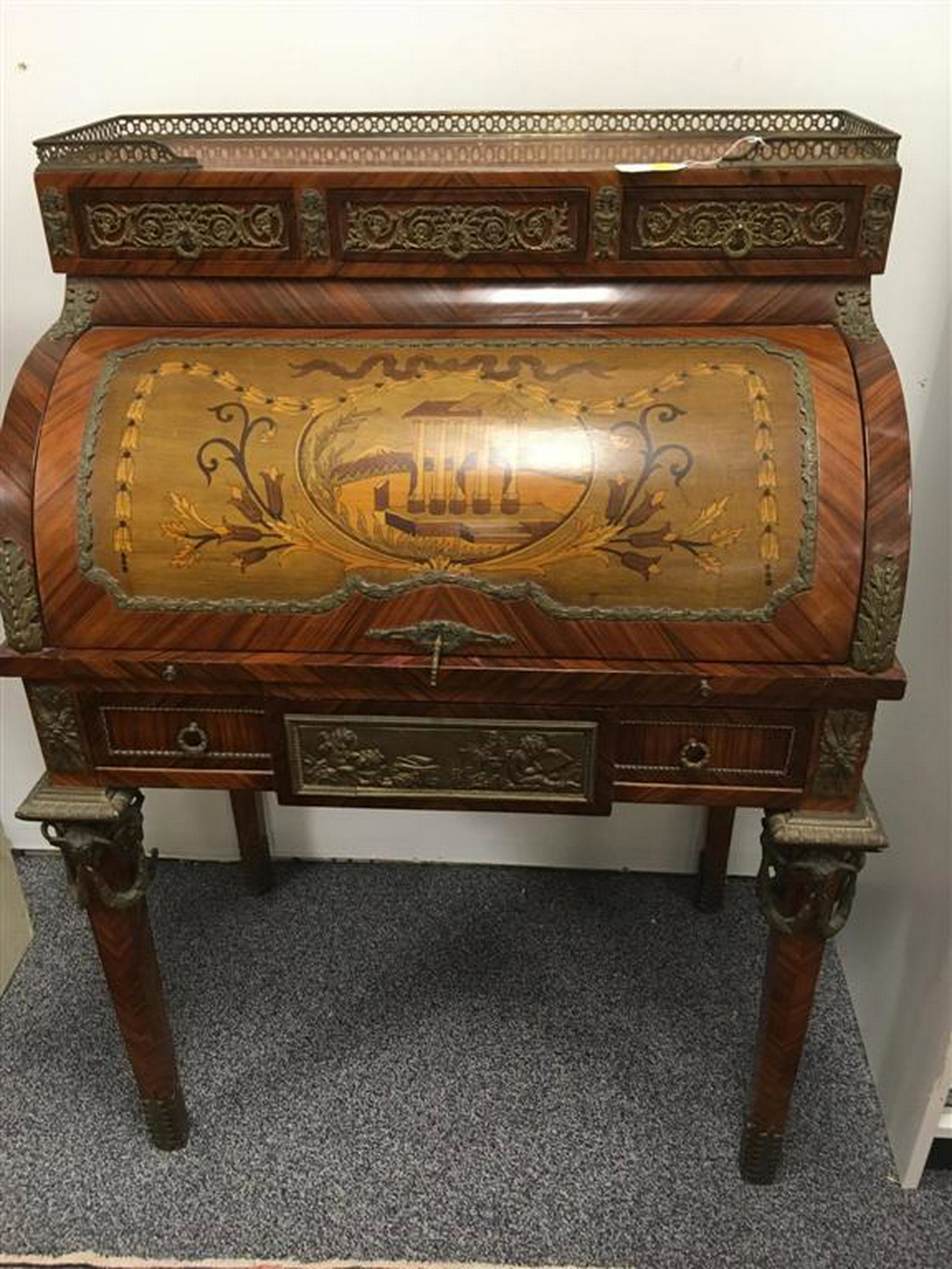 VINTAGE LOUIS XV STYLE CYLINDER DESK: Cylinder desk (early 20th C) - galleried top over 3 drawers, marquetry inlay cylinder, fitted 3 drawer interior, pull out writing surface, over one large drawer. Ornate ormolu mounts including ram's h