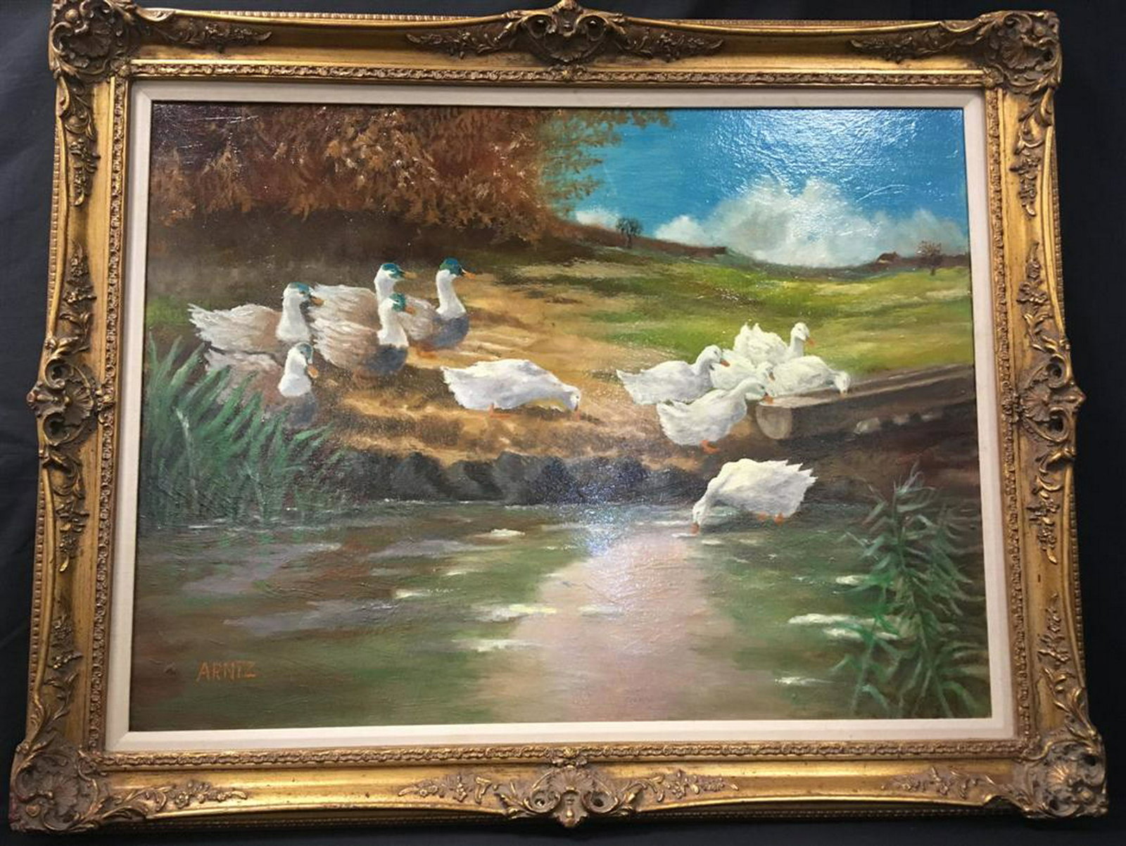 LARGE IMPRESSIONIST PAINTING OF DUCKS: A large framed impressionist painting depicting a flock of ducks by a lake with foliage and trees. Signed Arntz lower left. Framed measurement: 38" x 48" x 3 1/2". Condition is good.